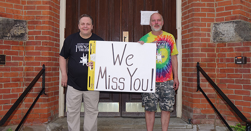 Towngate Theatre staff hold a sign that says, "We Miss You."